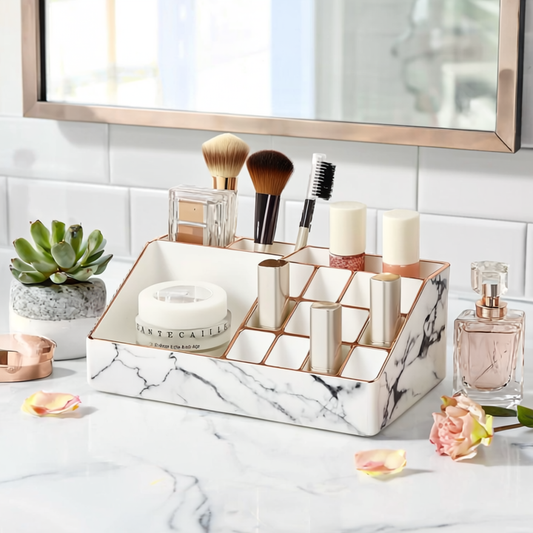 Marble-patterned cosmetic organizer with makeup brushes, candles, and a perfume bottle on a bathroom counter.