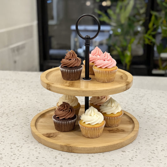 Two-tier wooden cupcake stand with cupcakes on a light surface.