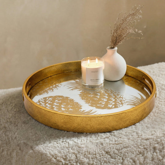 Gold decorative tray with a candle and vase on a textured surface
