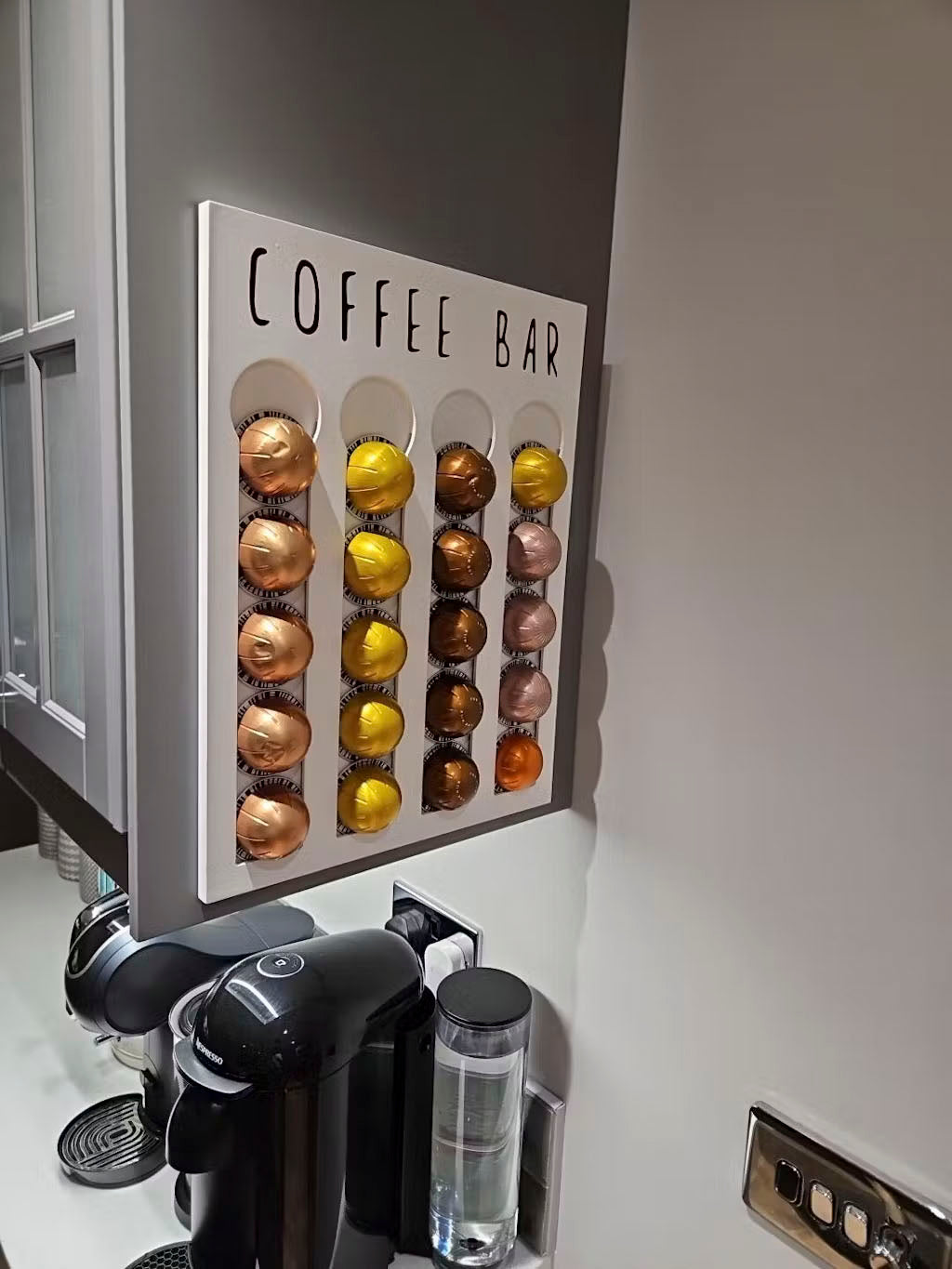 Coffee pod holder with assorted coffee pods next to a coffee machine.