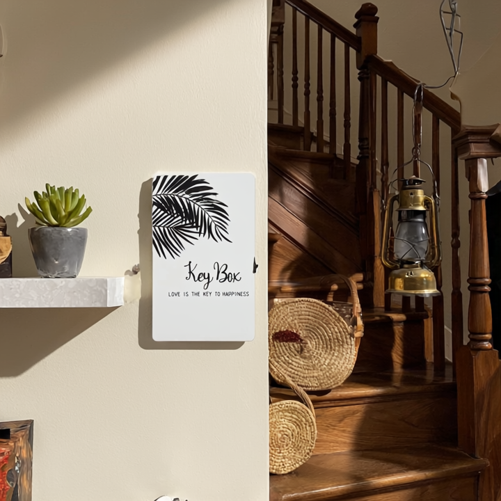 Key box with leaf design on a wall next to a wooden staircase with lanterns.