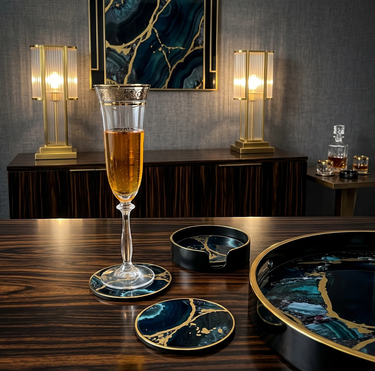A luxury bar set featuring a black and teal agate-patterned glassware and tableware collection with gold metallic accents, styled on a dark wood table with a glass of amber beverage in the center.