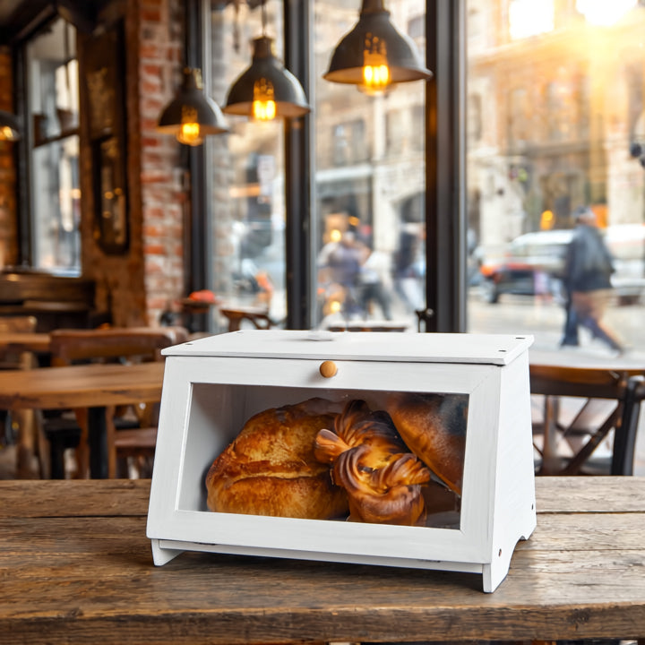White bread box with loaves of bread on a wooden table in a cafe setting.