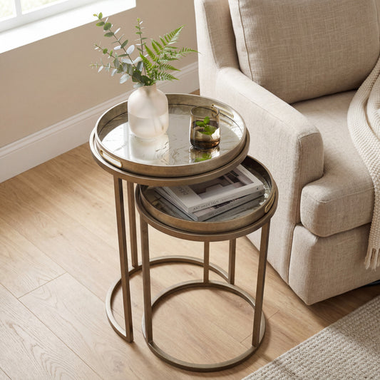Round metal side table with a plant and books in a living room setting.