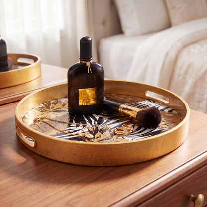 Decorative tray with a perfume bottle, makeup brush, and rings on a wooden surface.