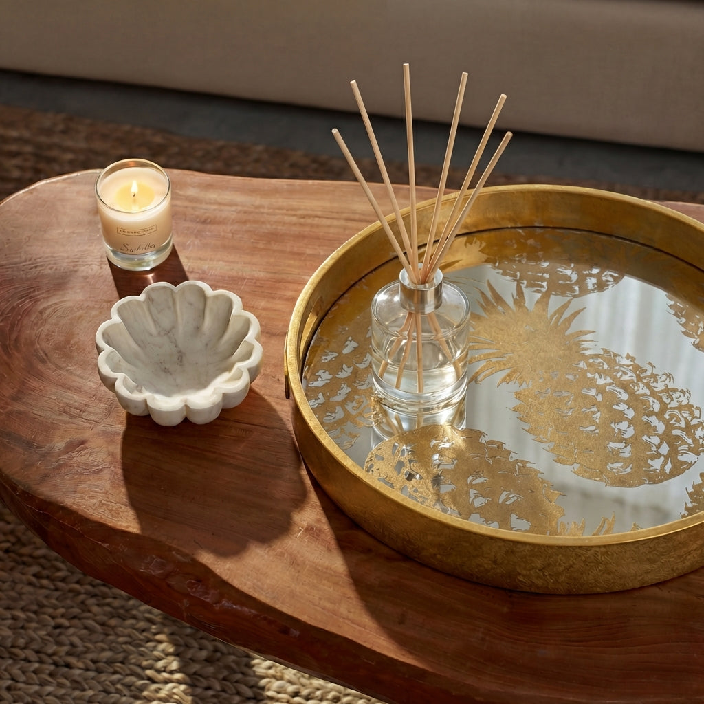 Decorative items including a candle, shell dish, and reed diffuser on a wooden table.
